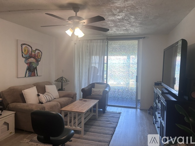 A living room with a brown couch, a black chair, a wooden coffee table, a flat screen TV, and a painting on the wall.