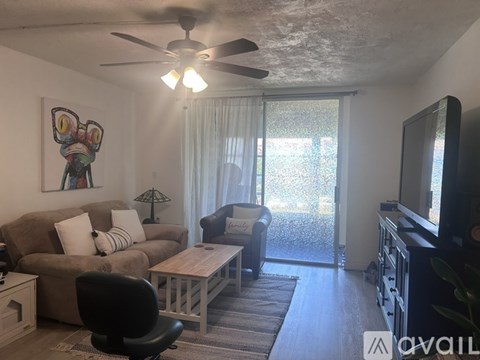 A living room with a brown couch, a black chair, a wooden coffee table, a flat screen TV, and a painting on the wall.