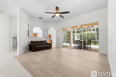 A living room with a brown couch and a ceiling fan.