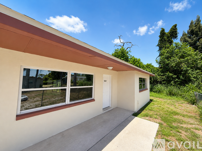 A house with a brown roof and white walls has a small front yard.