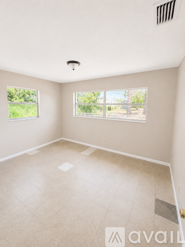 A room with a tiled floor and a window overlooking a green area.