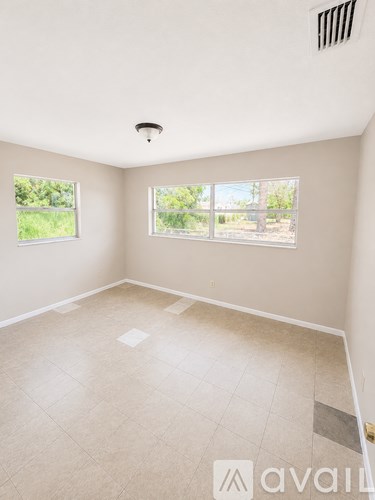 A room with a tiled floor and a window overlooking a green area.