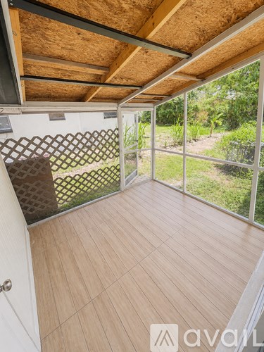 A room with wooden flooring and a sliding glass door leading to a garden.