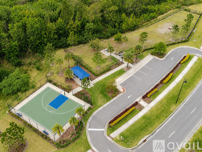 A basketball court is surrounded by a fence and a small pool.