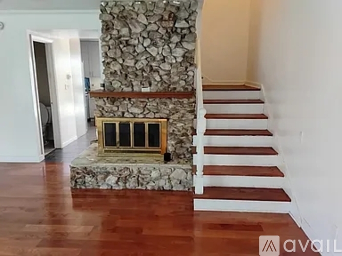 A stone staircase with a wooden handrail and steps leading up to a doorway.