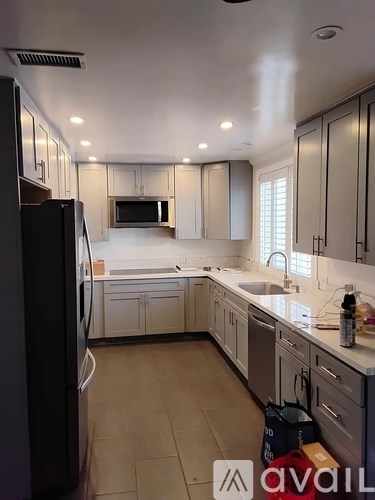 A kitchen with a black refrigerator and white cabinets.