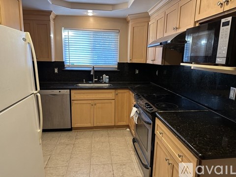A kitchen with black countertops and wooden cabinets.