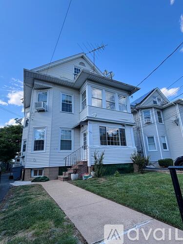 A two-story house with a front yard and a sidewalk.