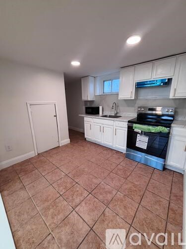 A kitchen with white cabinets and a tile floor.