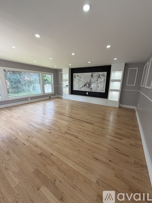A spacious room with wooden flooring and a large window.