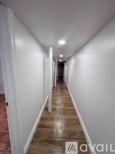 A long hallway with white walls and wood flooring.