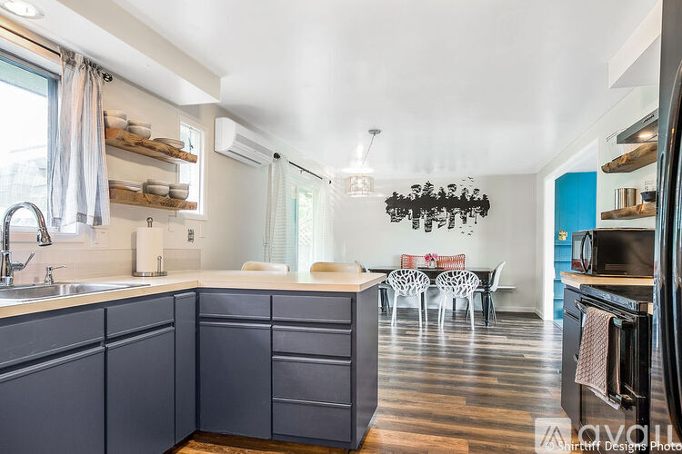 A kitchen with dark blue cabinets and a dining area with white chairs.