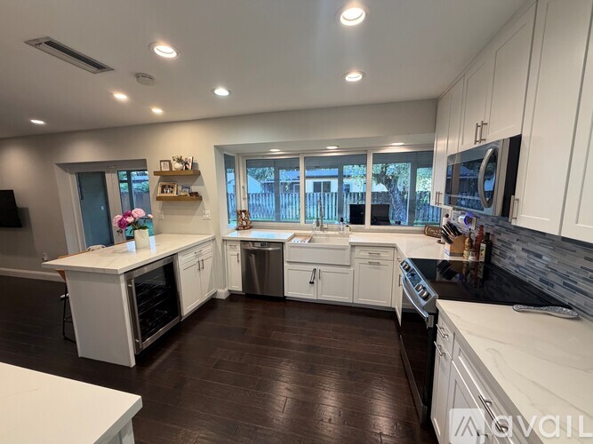 A modern kitchen with white cabinets and dark wood floors.