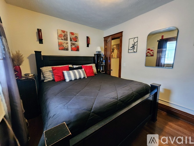 A bedroom with a black bed and red pillows.