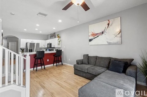 A living room with a grey couch and a painting on the wall.