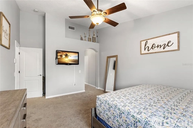 A bedroom with a bed, dresser, and a ceiling fan.