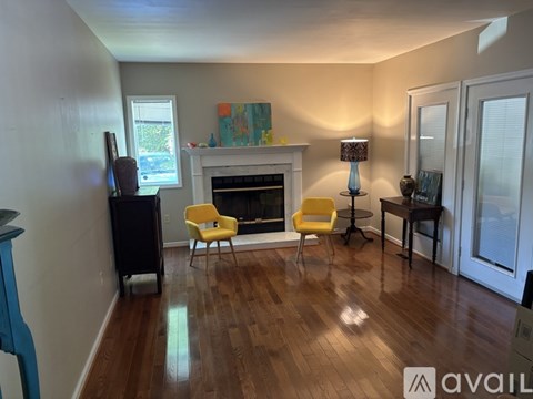 A living room with a fireplace, a yellow chair, and a painting on the wall.