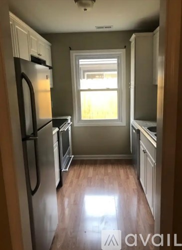 A kitchen with a refrigerator, oven, and a window.