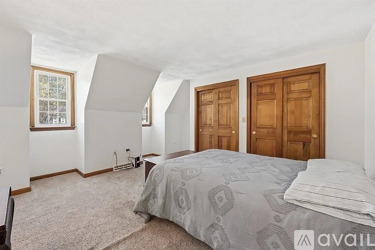 A bedroom with a bed, two doors, and a window.