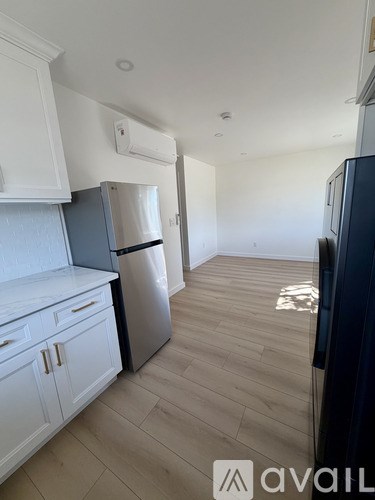 A kitchen with white cabinets and a black fridge.
