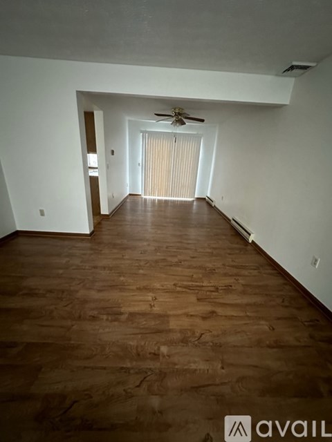 A room with wooden flooring and a ceiling fan.