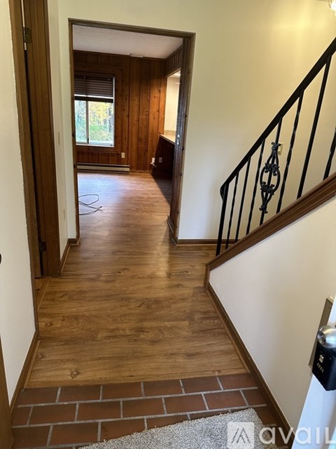 A hallway with wooden floors and a black metal railing.