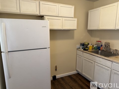 A white refrigerator in a kitchen with white cabinets.