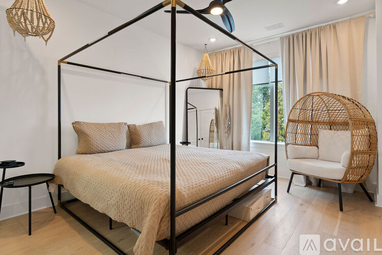 A bedroom with a four-poster bed and a wicker chair.