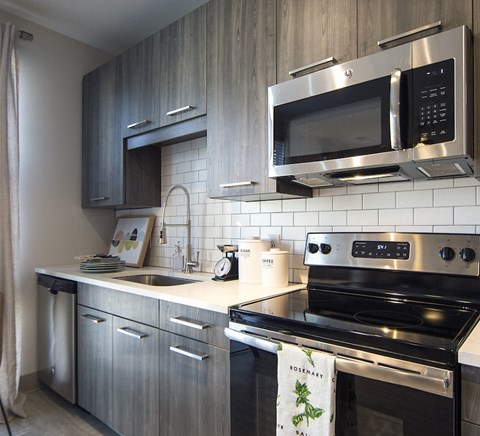 A modern kitchen with a stove top oven and a microwave above it.