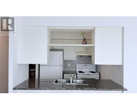 A kitchen with a sink, stove, and cabinets.