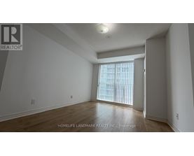 A room with a window covered by blinds, and a logo of a realtor company on the top left corner.