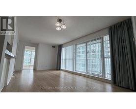 A spacious room with a large window and wooden flooring.