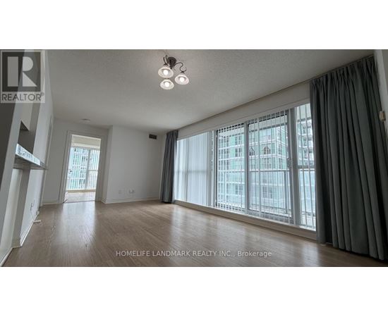 A spacious room with a large window and wooden flooring.