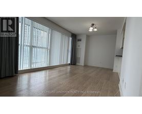A room with wooden flooring and a large window with blinds.
