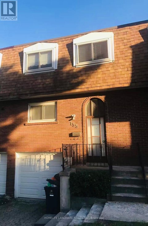 A red brick house with a white garage door and a black gate.