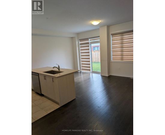 A kitchen with a sink and cabinets in a room with a sliding glass door.