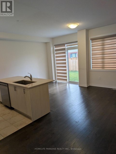 A kitchen with a sink and cabinets in a room with a sliding glass door.