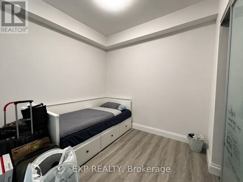 A bedroom with a bed, drawers, and a suitcase.