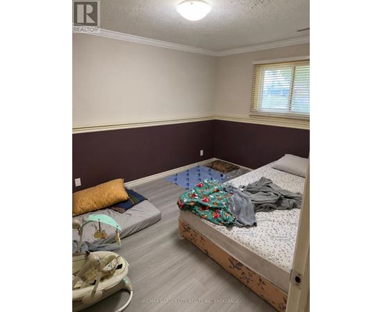 A bedroom with a bed, a baby bouncer, and a window.
