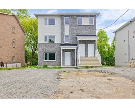 A two-story house with a gravel driveway in front.