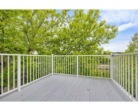 A white deck with a railing and trees in the background.