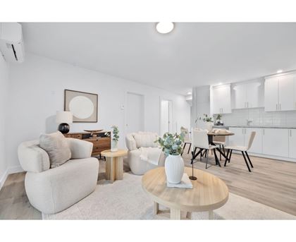 A living room with a white couch, a wooden coffee table, and a dining table with chairs.