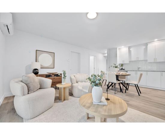 A living room with a white couch, a wooden coffee table, and a dining table with chairs.