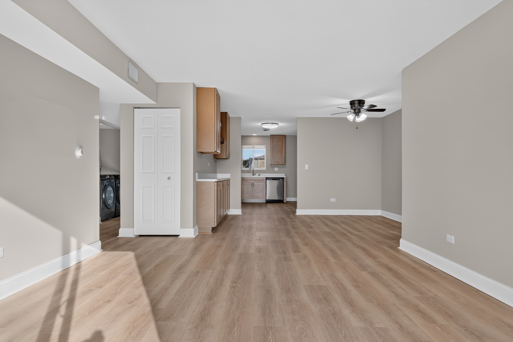 A spacious room with wooden flooring and a ceiling fan.