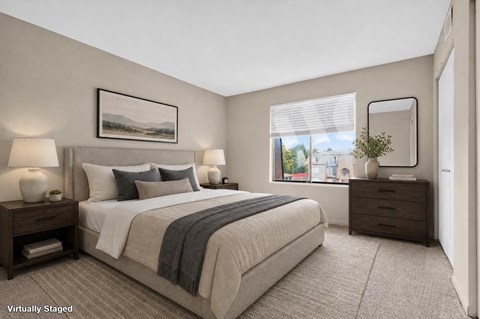 A bedroom with a large bed, two nightstands, and a window overlooking a cityscape.