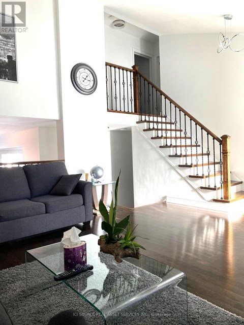 A living room with a grey couch and a glass coffee table.