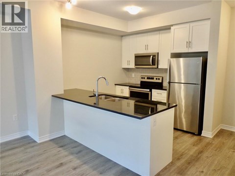 A modern kitchen with a black countertop and stainless steel appliances.