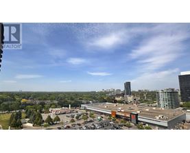 A view of a cityscape with a large building in the foreground and a parking lot with cars.