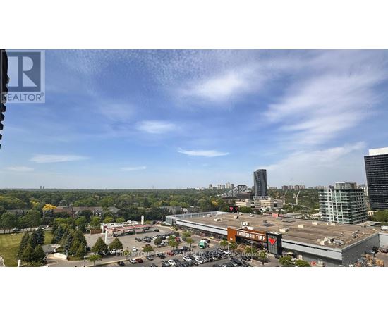 A view of a cityscape with a large building in the foreground and a parking lot with cars.