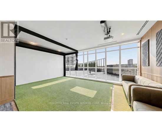 A spacious living room with a green carpet and a large window overlooking a cityscape.